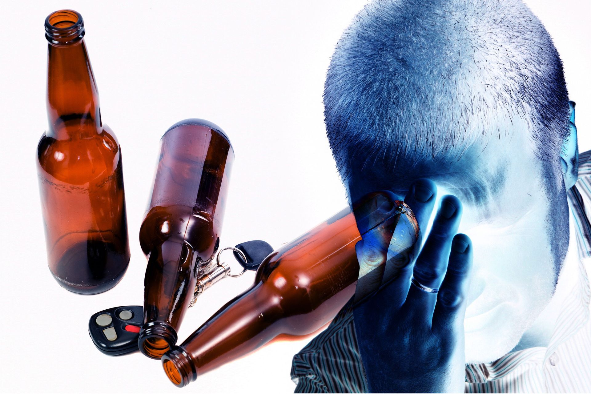 A man covering his face with a beer bottle and a car key