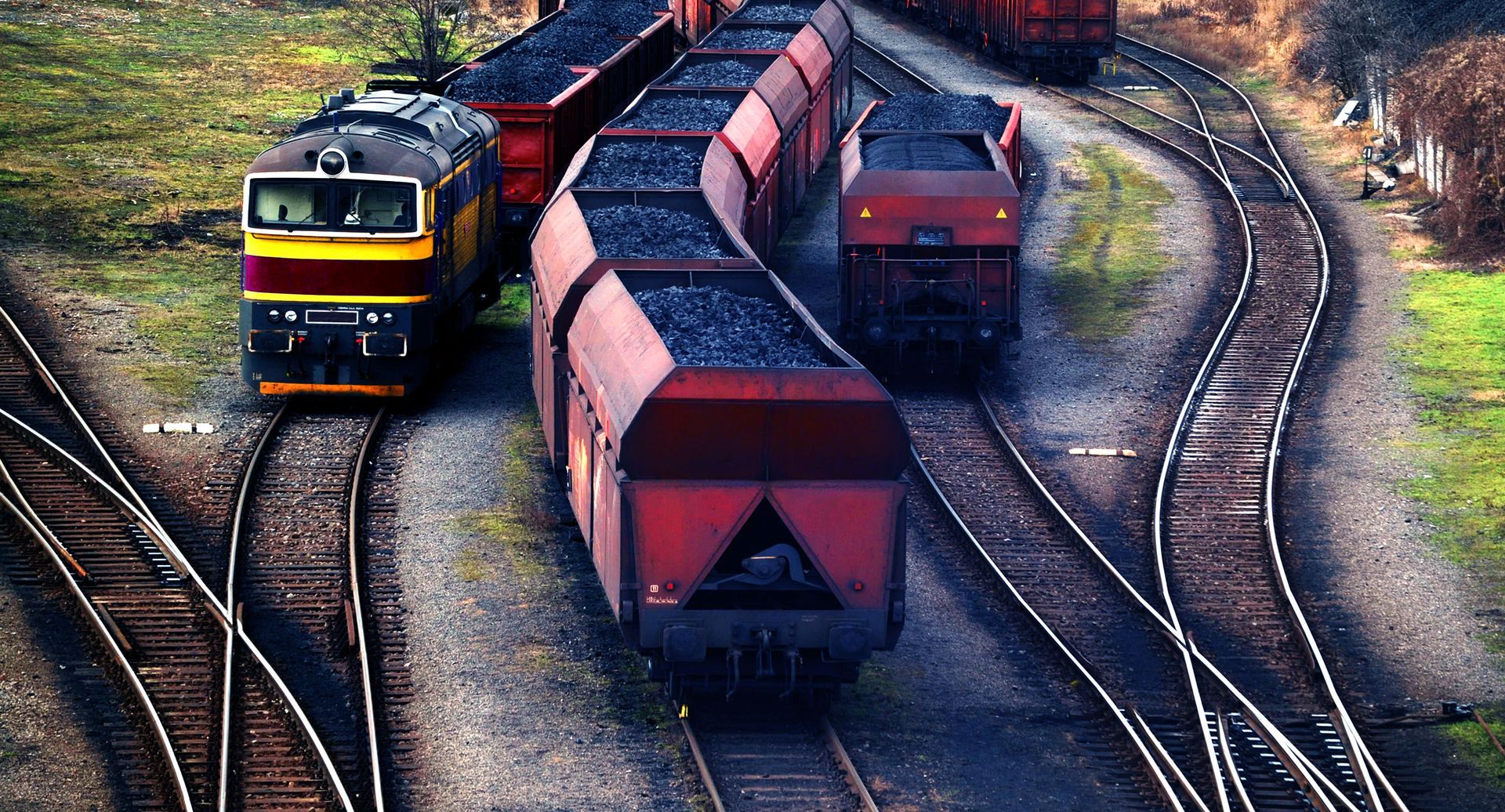 A train is going down the tracks carrying coal.