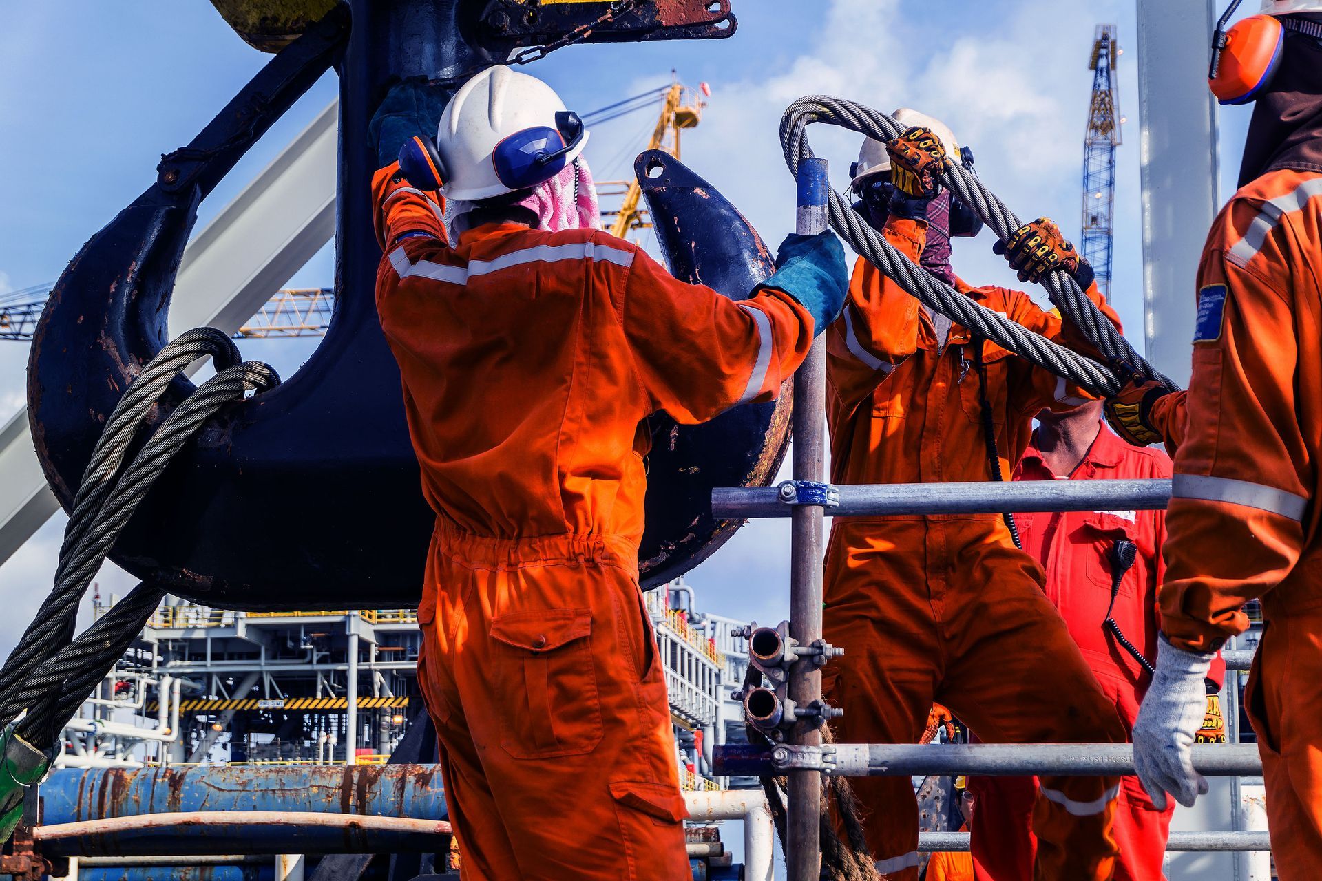 A group of men in orange jumpsuits are working on a boat.