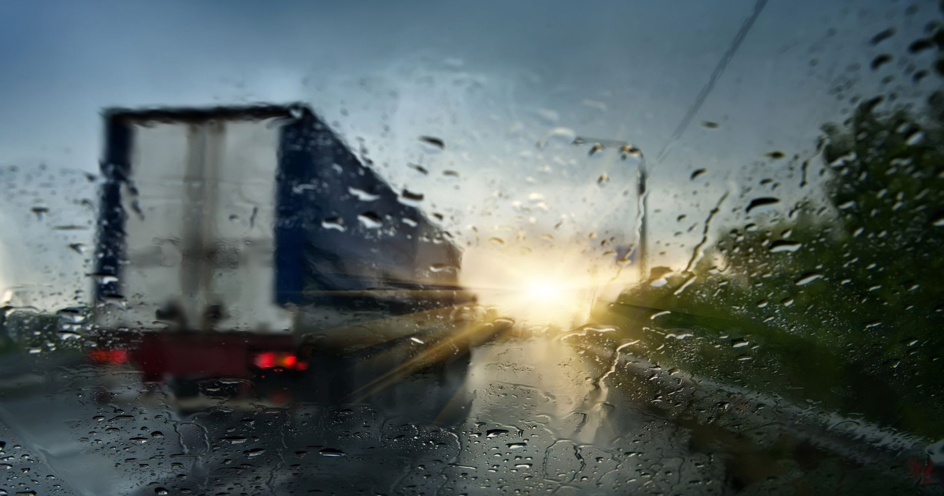 A truck is driving down a wet highway in the rain.