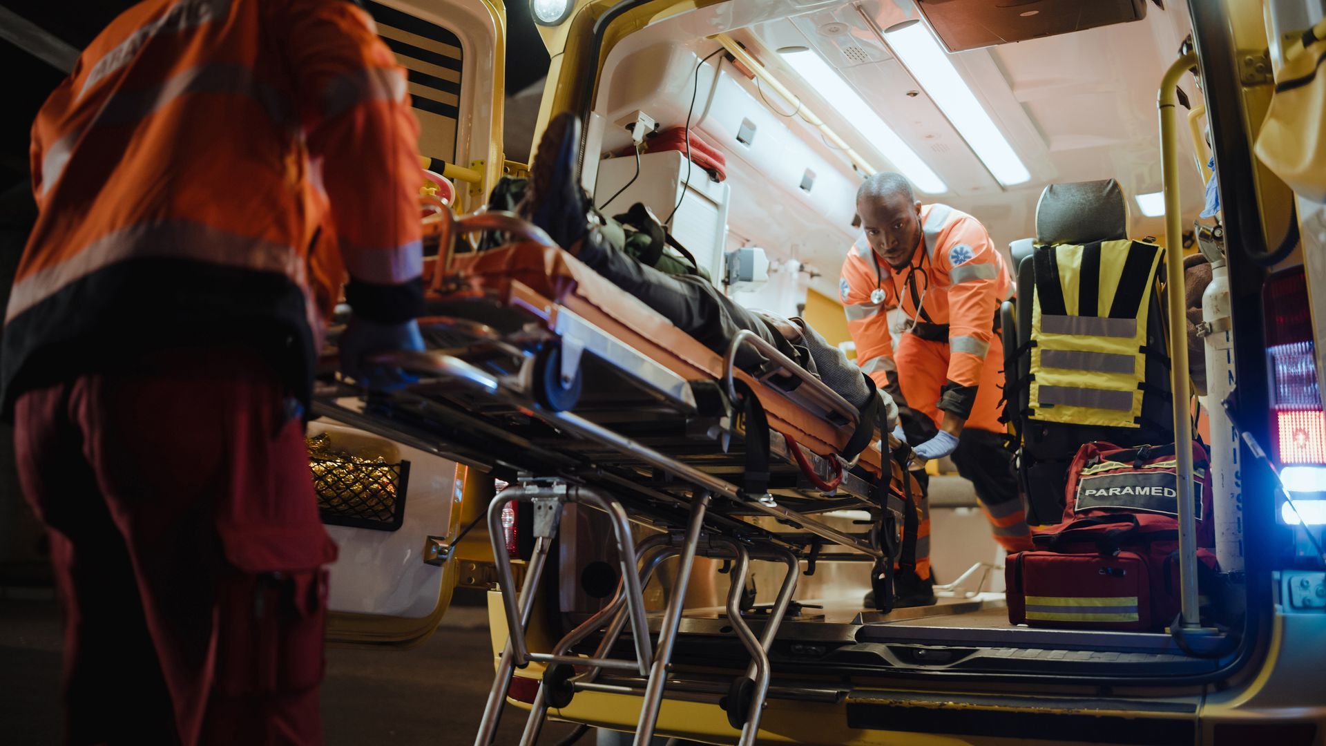 A man is loading a stretcher into an ambulance.