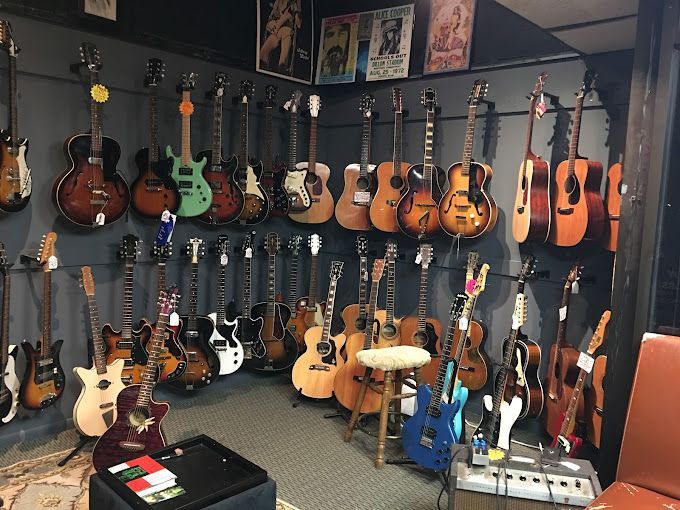 A room filled with lots of guitars hanging on a wall