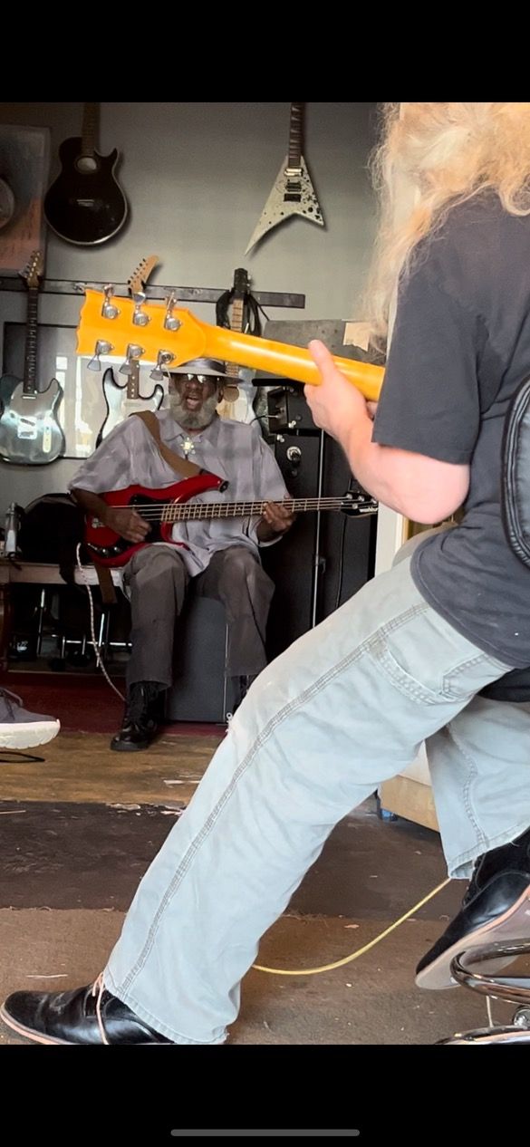 A bunch of guitars are hanging on a wall with a marshall amp in the background