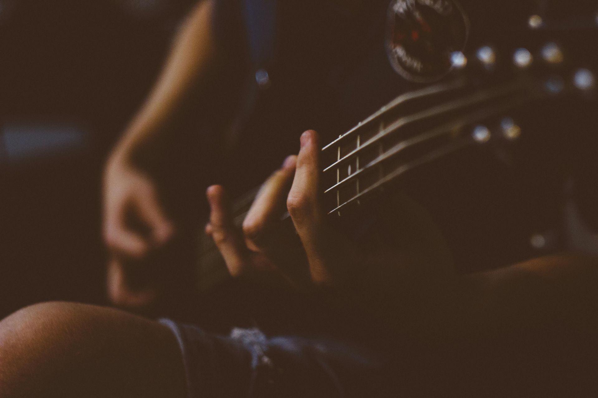 A person is playing a guitar in a dark room.