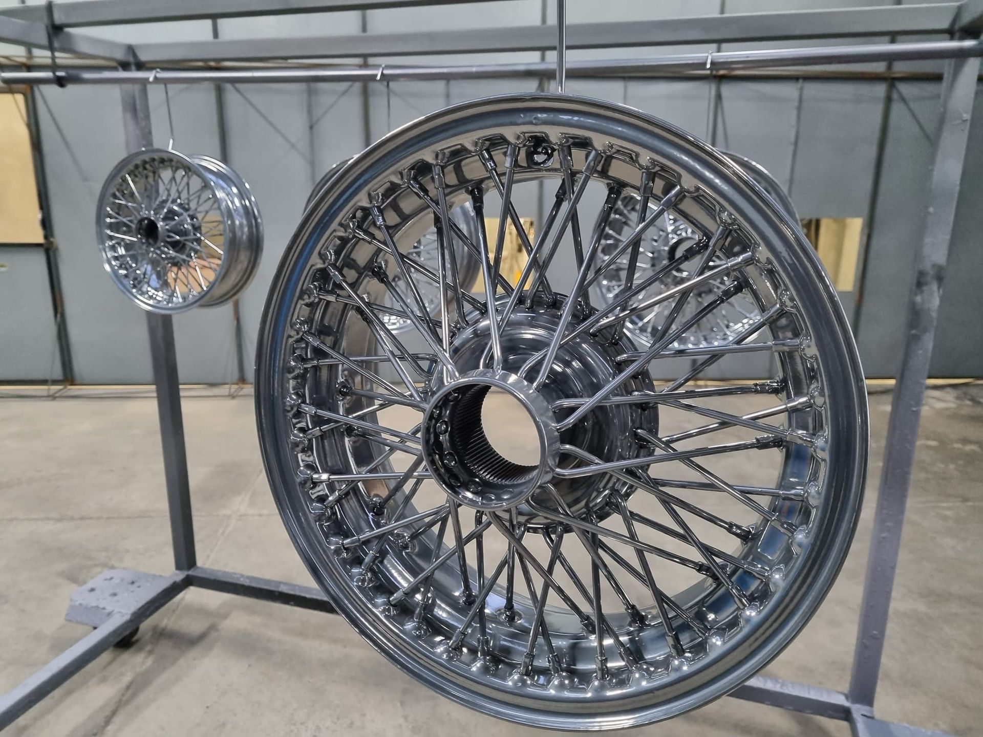 Two Shiny Chrome Wire Wheels Hanging on a Rack in a Workshop — SPW Engineering & Powdercoating In Ballarat, VIC