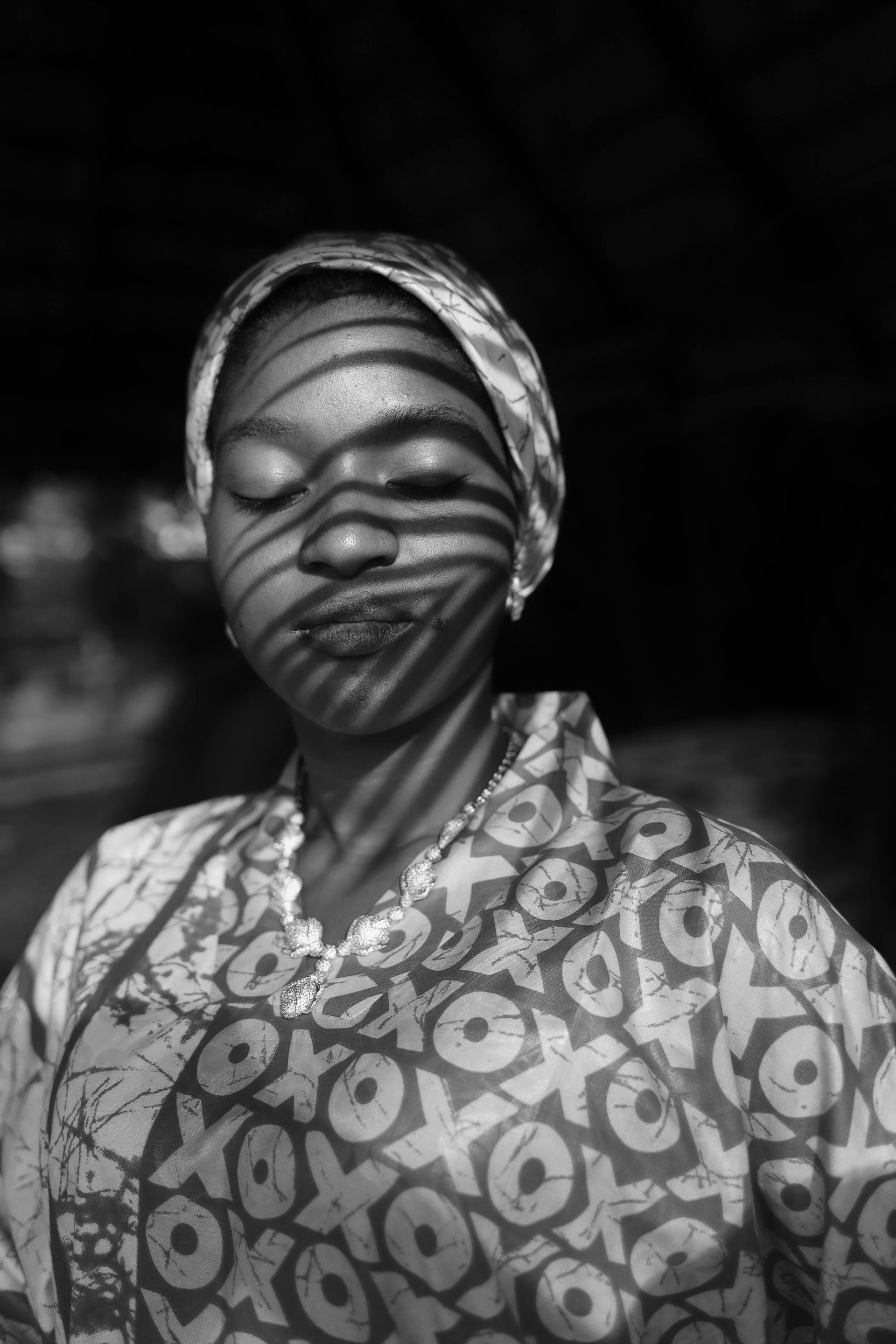 A black and white photo of a woman with shadows on her face