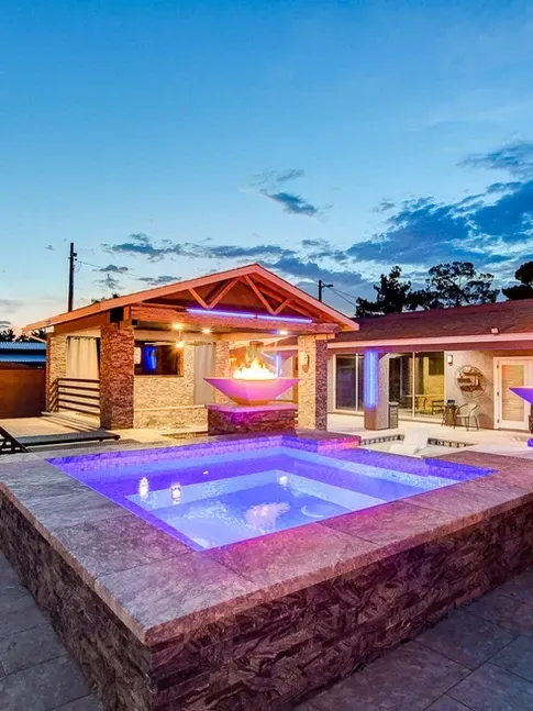 A large swimming pool with a fire pit in the backyard of a house.