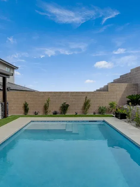 There is a large swimming pool in the backyard of a house.