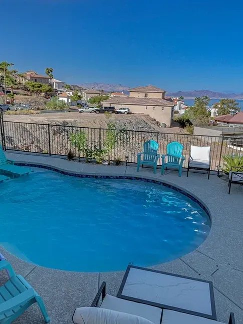 There is a large swimming pool with chairs around it.