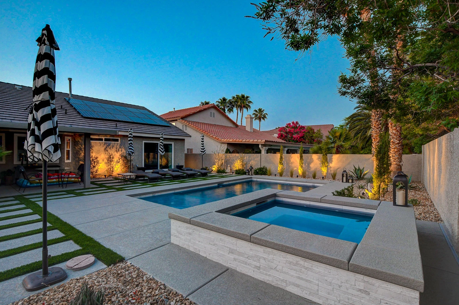 A large swimming pool and hot tub are in the backyard of a house.
