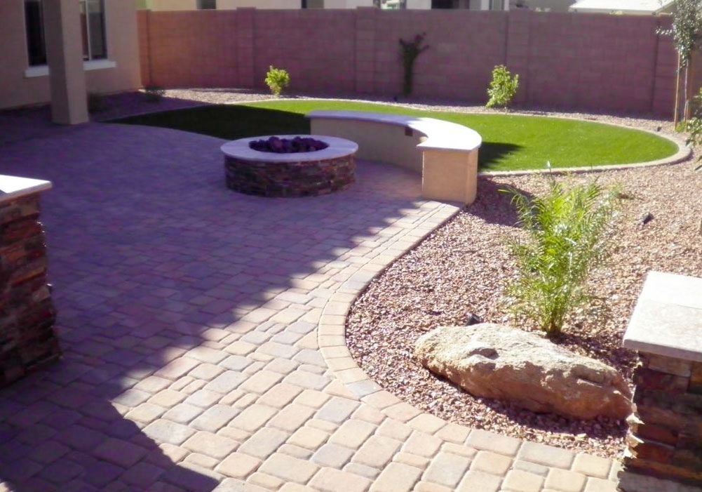 A patio with a fire pit and a bench