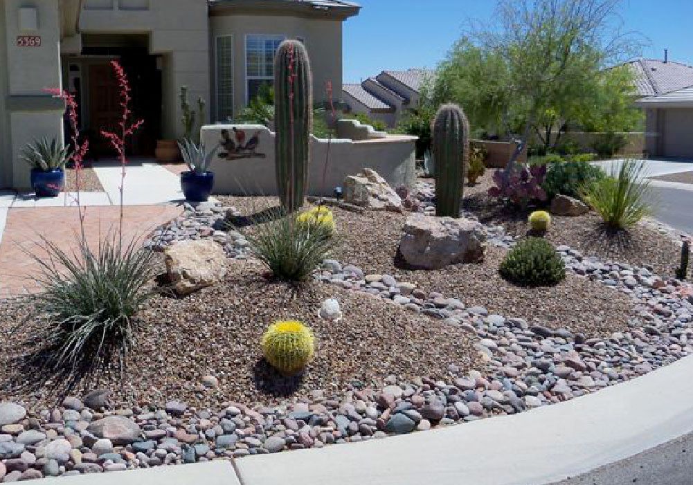 A garden with rocks and cactus in front of a house