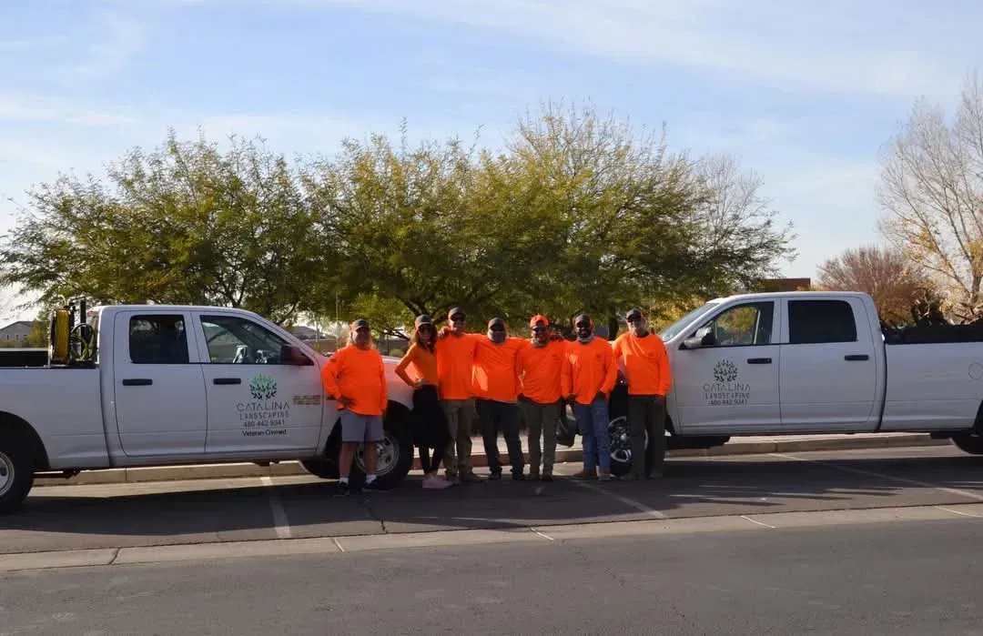 A group of people are posing for a picture in front of two trucks.