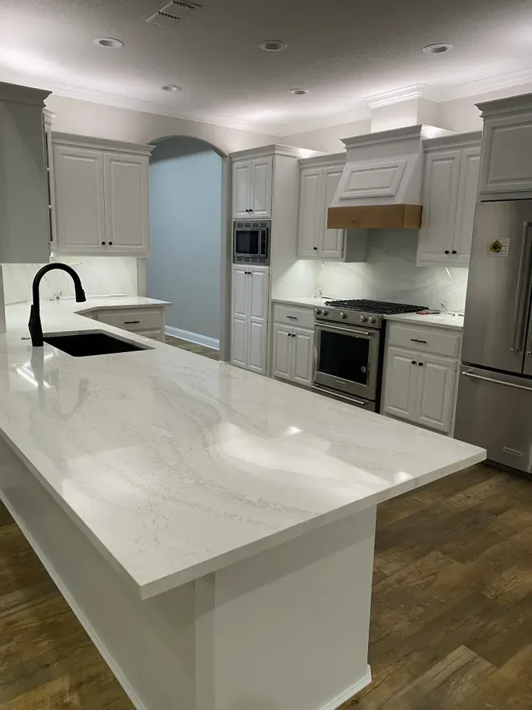Modern kitchen with white cabinets, quartz countertops, and stainless steel appliances.