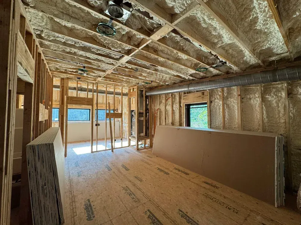 Interior of a room under construction with exposed wooden framing and insulation.