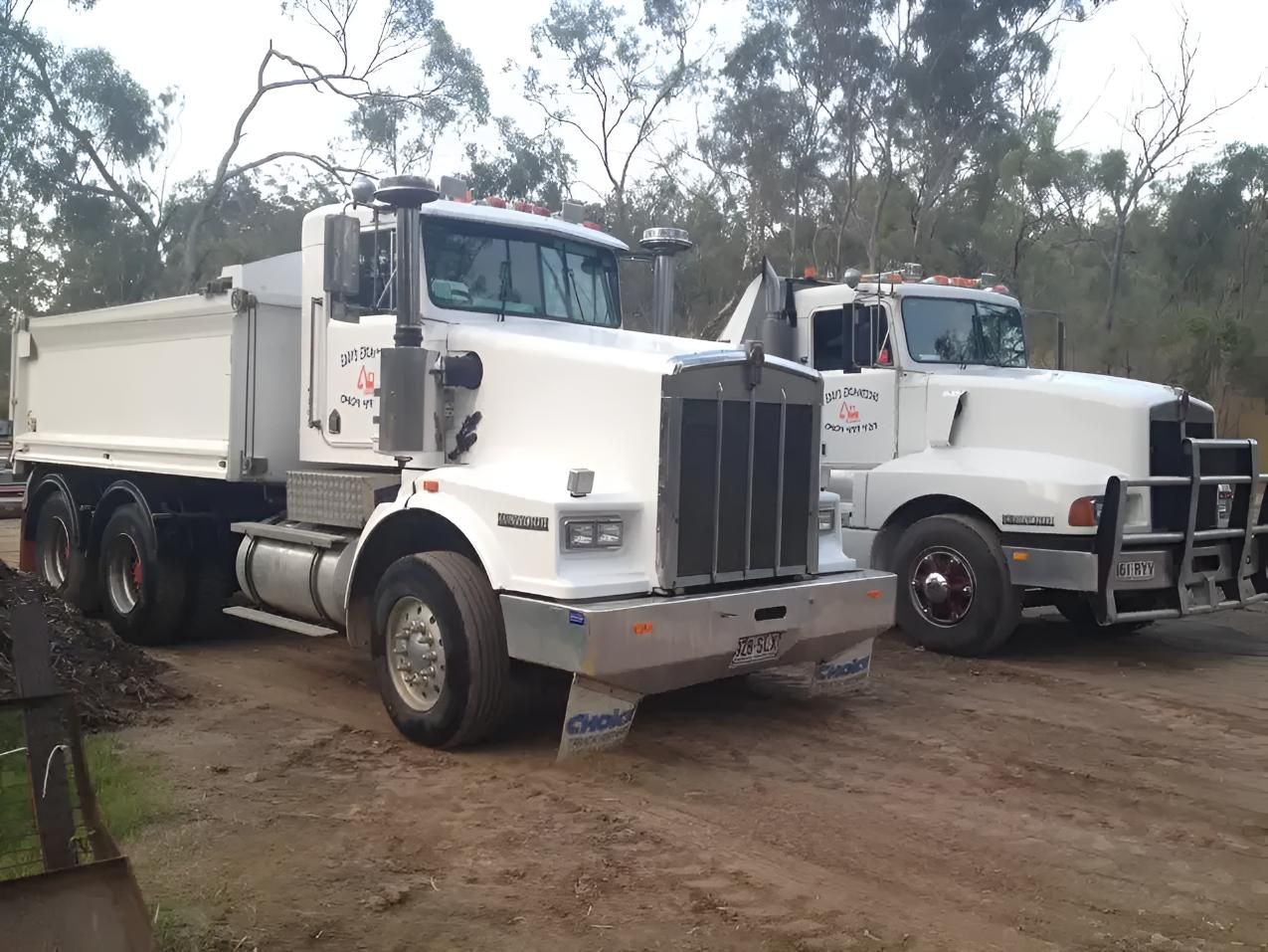 Two Dump Trucks Are Parked Next to Each Other on a Dirt Road — Eddy’s Excavations & Bobcat Hire In Wurdong Heights, QLD