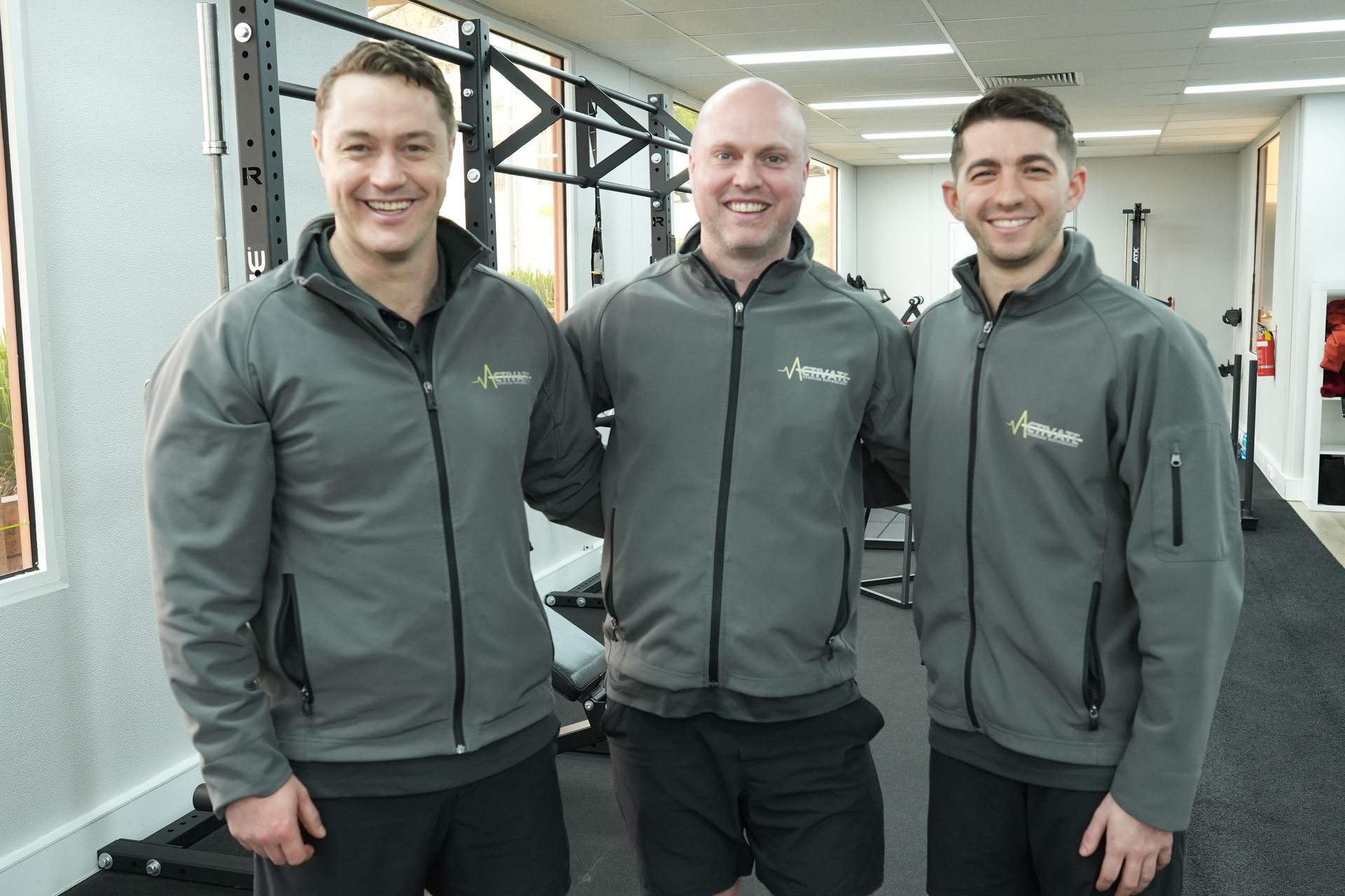 Three men are posing for a picture in a gym.