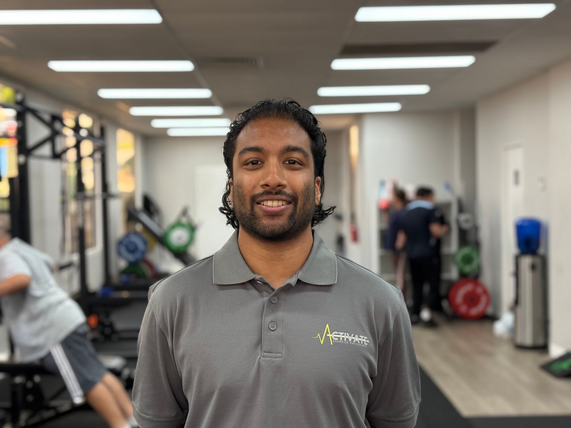 A man in a grey shirt is standing in a gym.