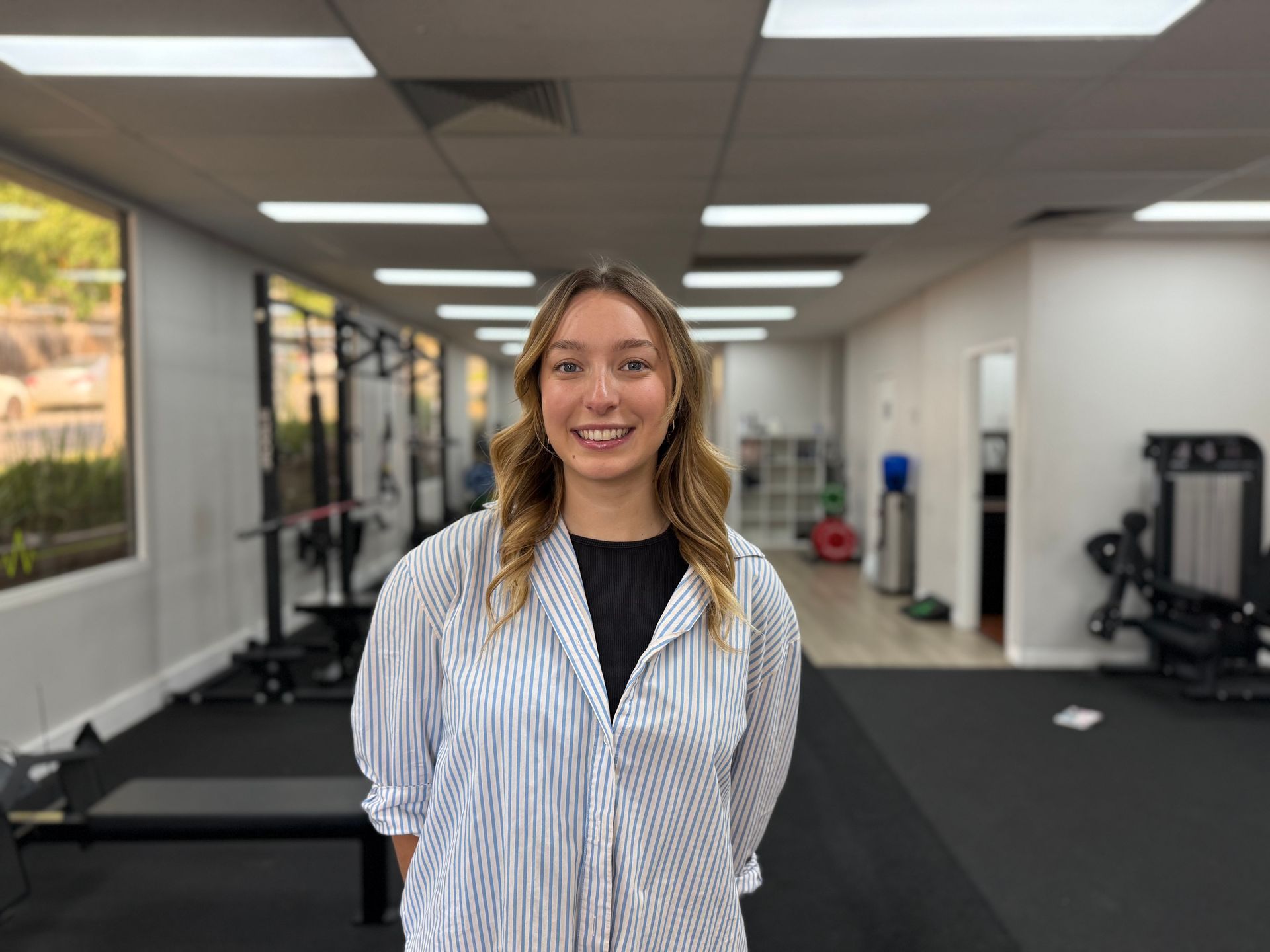 A woman in a striped shirt is standing in a gym.
