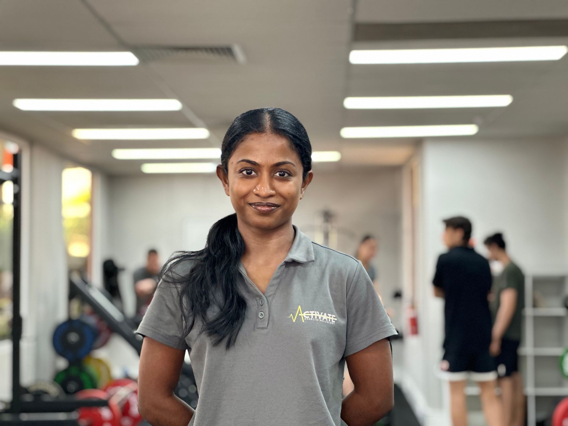A woman is standing in a gym with her hands on her hips.