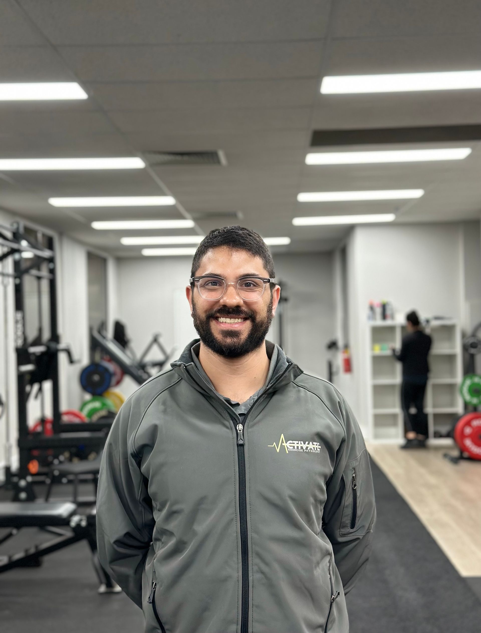 A man with a beard and glasses is standing in a gym.