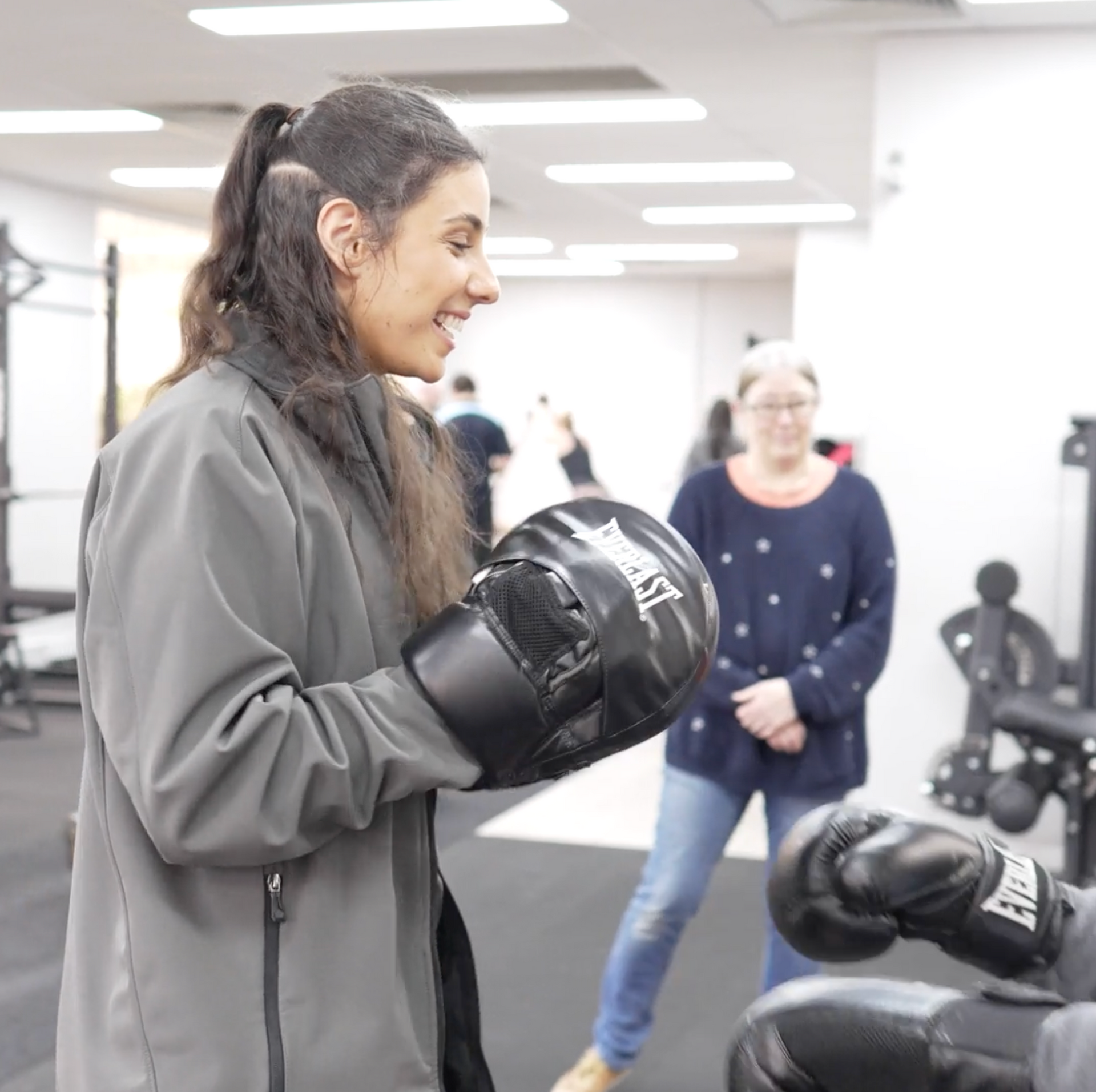 A woman wearing everlast boxing gloves in a gym