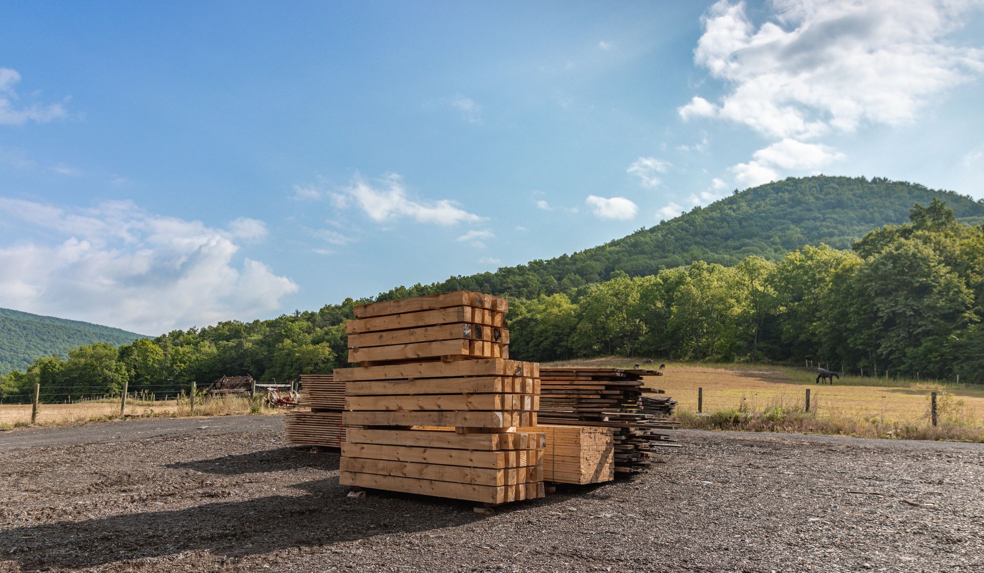 A stack of wooden pallets in a gravel lot with mountains in the background.