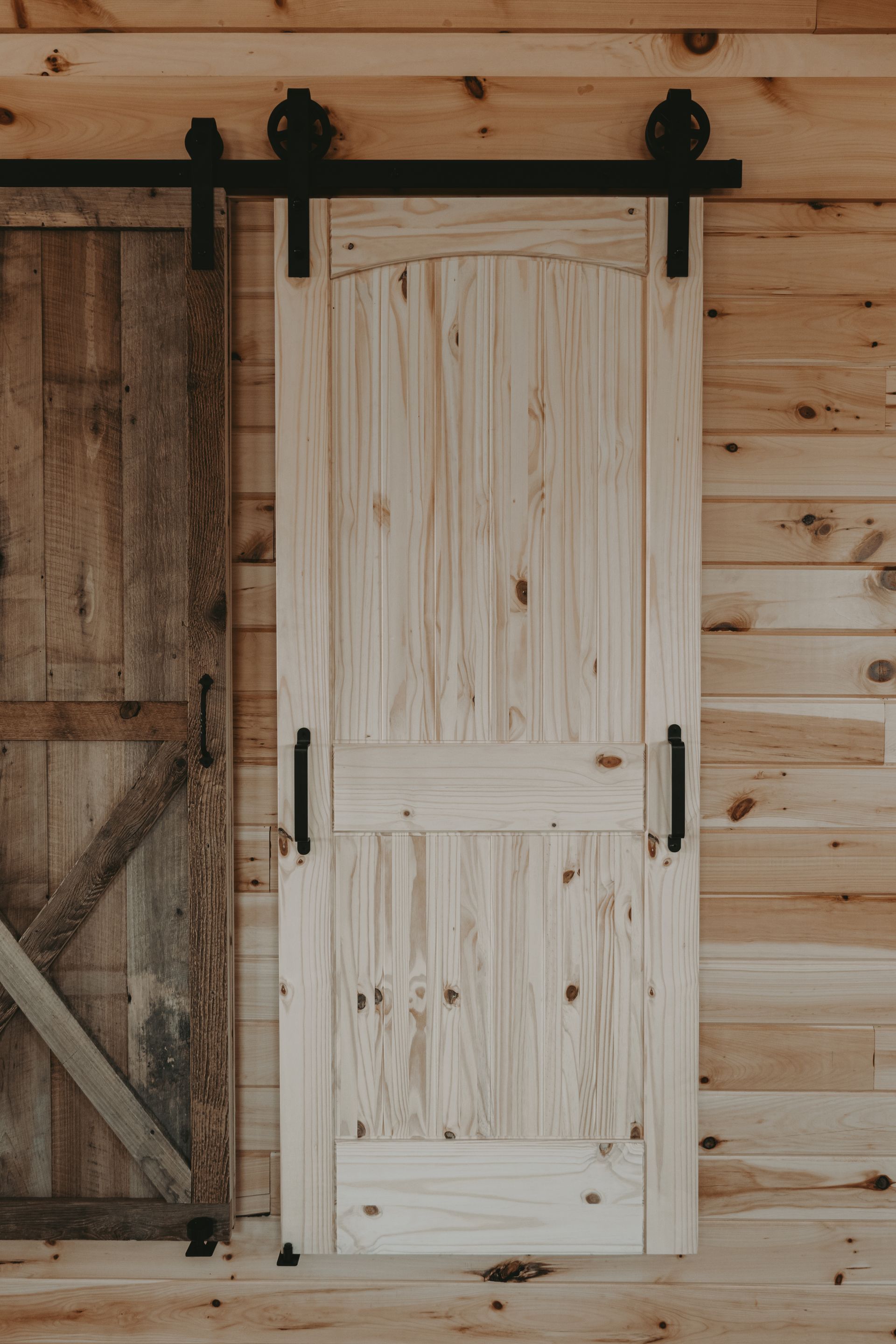 A sliding barn door is hanging on a wooden wall.