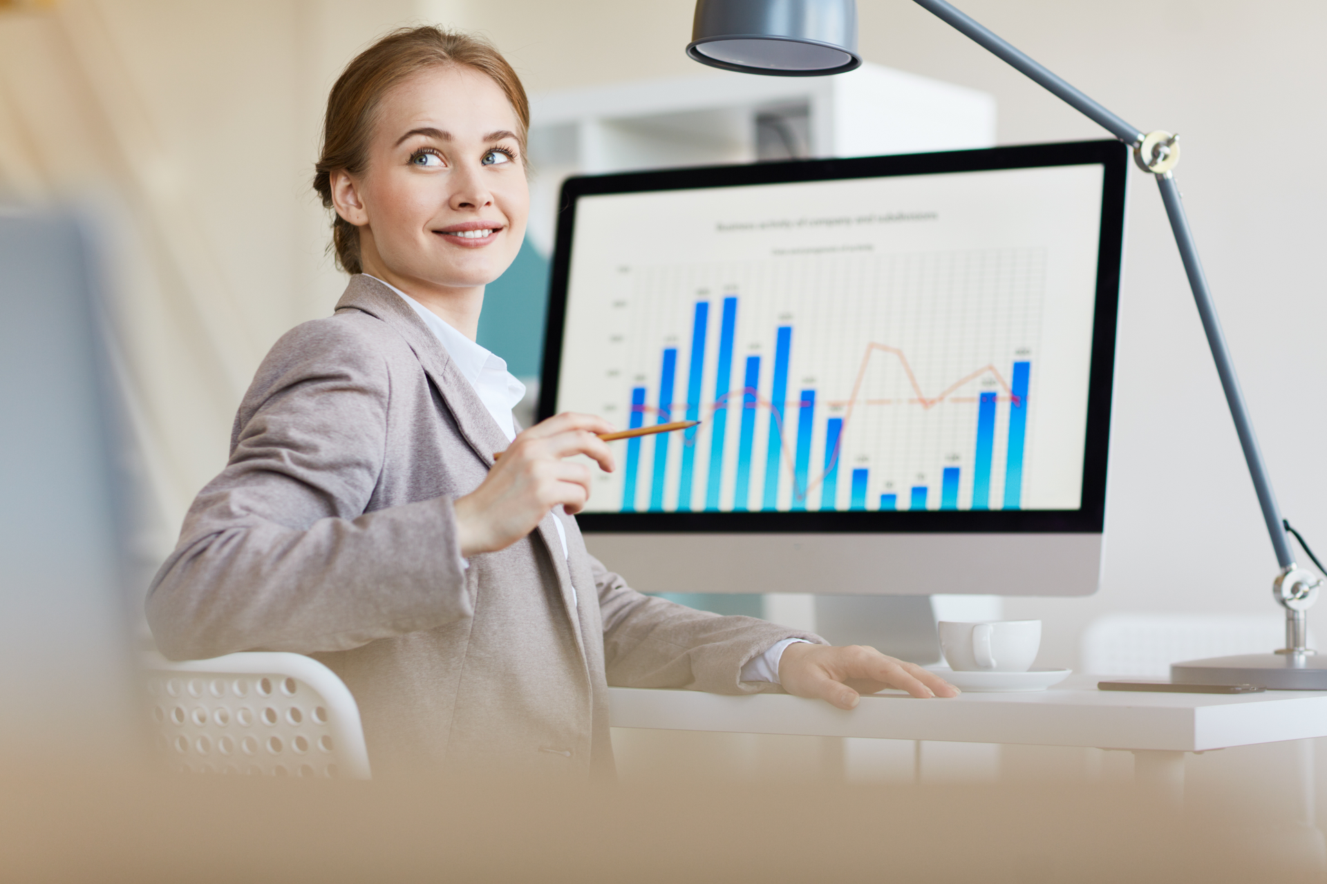 A woman is sitting at a desk in front of a computer screen.