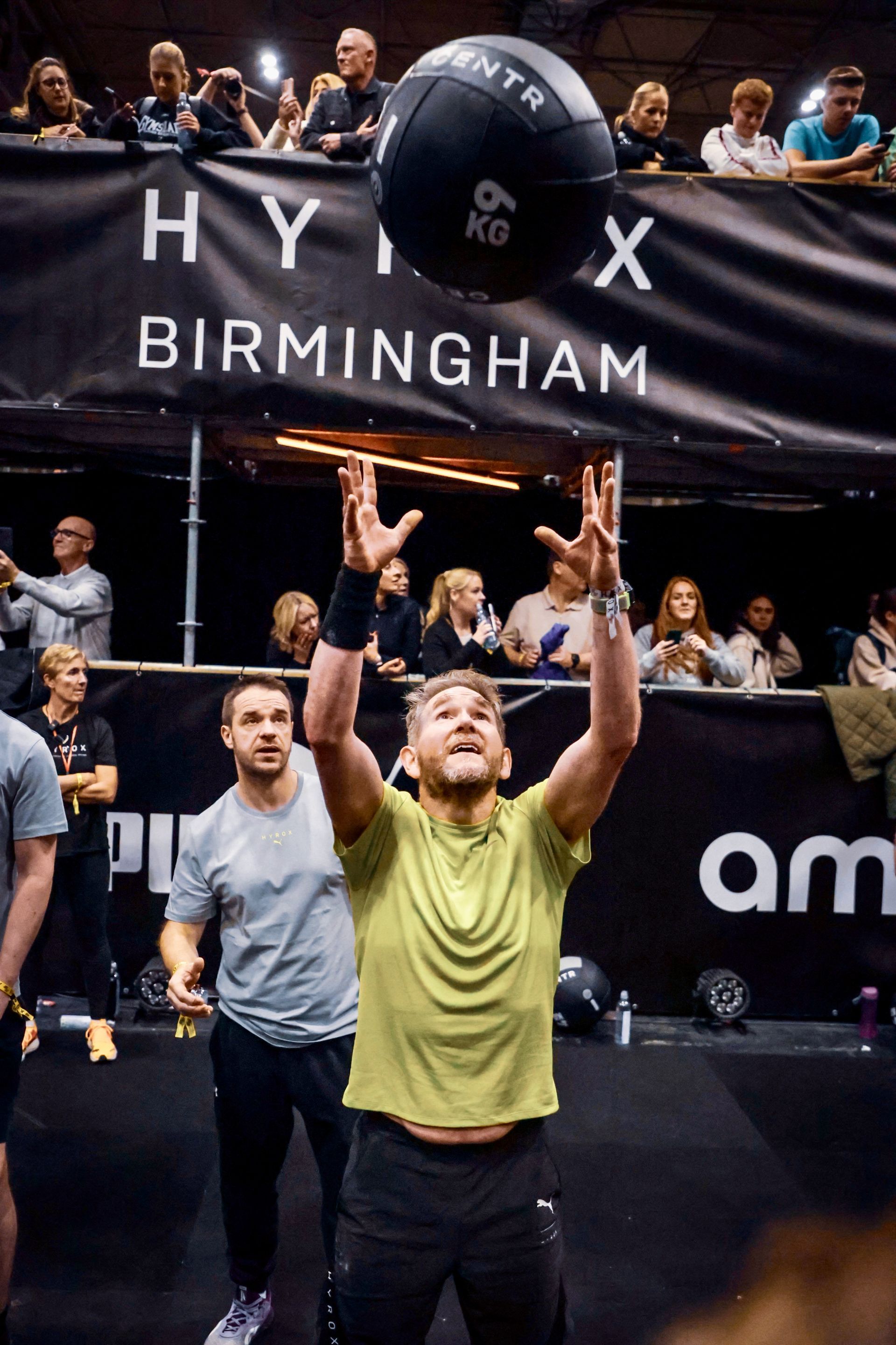 A man is throwing a ball in the air in front of a crowd.