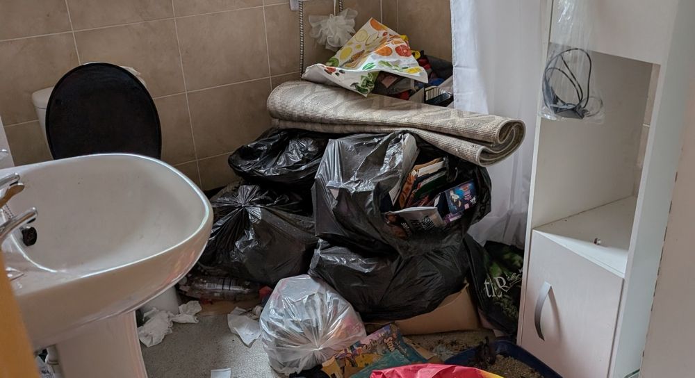 Cluttered bathroom: black trash bags, rug, and a sink. before cleanup
