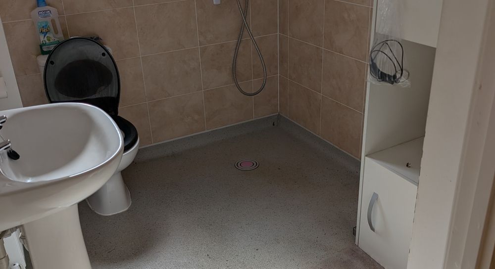 Bathroom with a toilet, sink, and cabinet against tiled walls and a neutral-coloured floor. after clean up