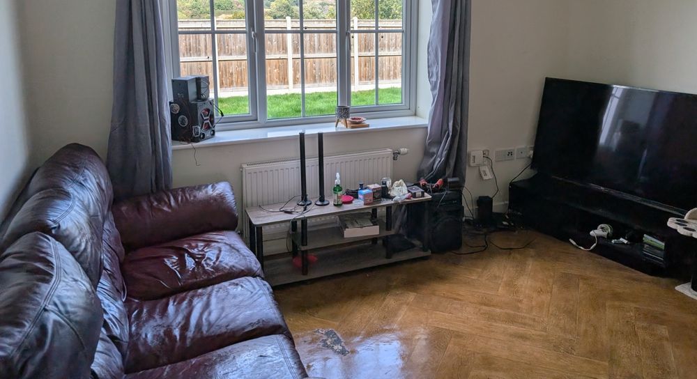 Living room with a leather sofa, window, TV, and electronics on a shelf. after clean up