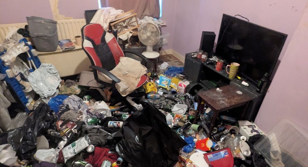 Messy room with trash, clothes, and various items scattered throughout. A computer and TV are visible. before clean up