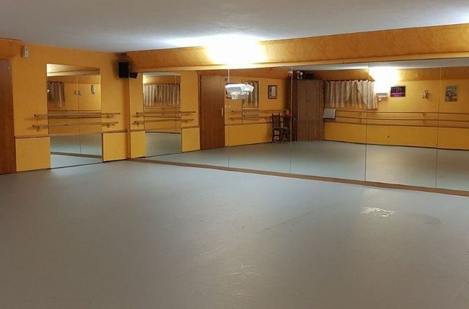 Studio de danse vide avec miroirs, murs jaunes et sol gris