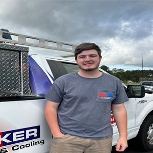 A man is standing in front of a truck that says ker on it.