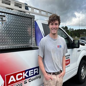 A man is standing in front of an acker heating and cooling truck.
