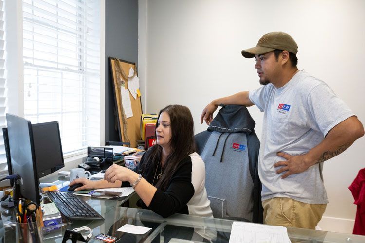 A man and a woman are standing next to each other in front of a computer.