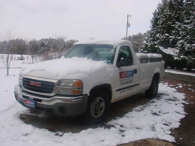A white gmc truck is parked in the snow