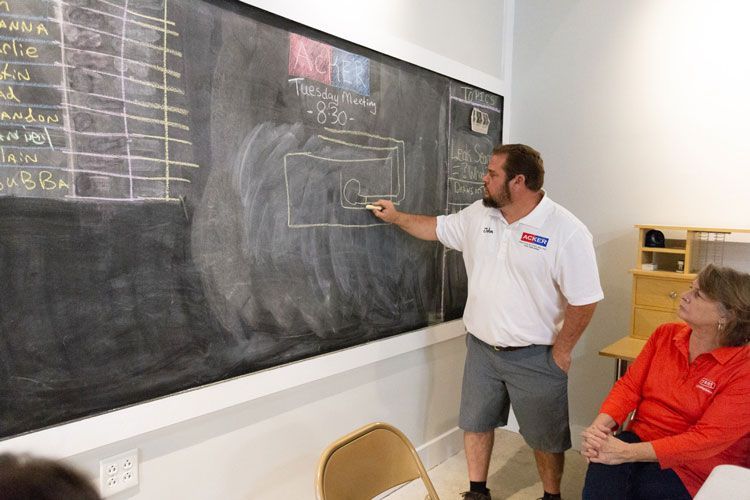 A man is standing in front of a blackboard giving a presentation