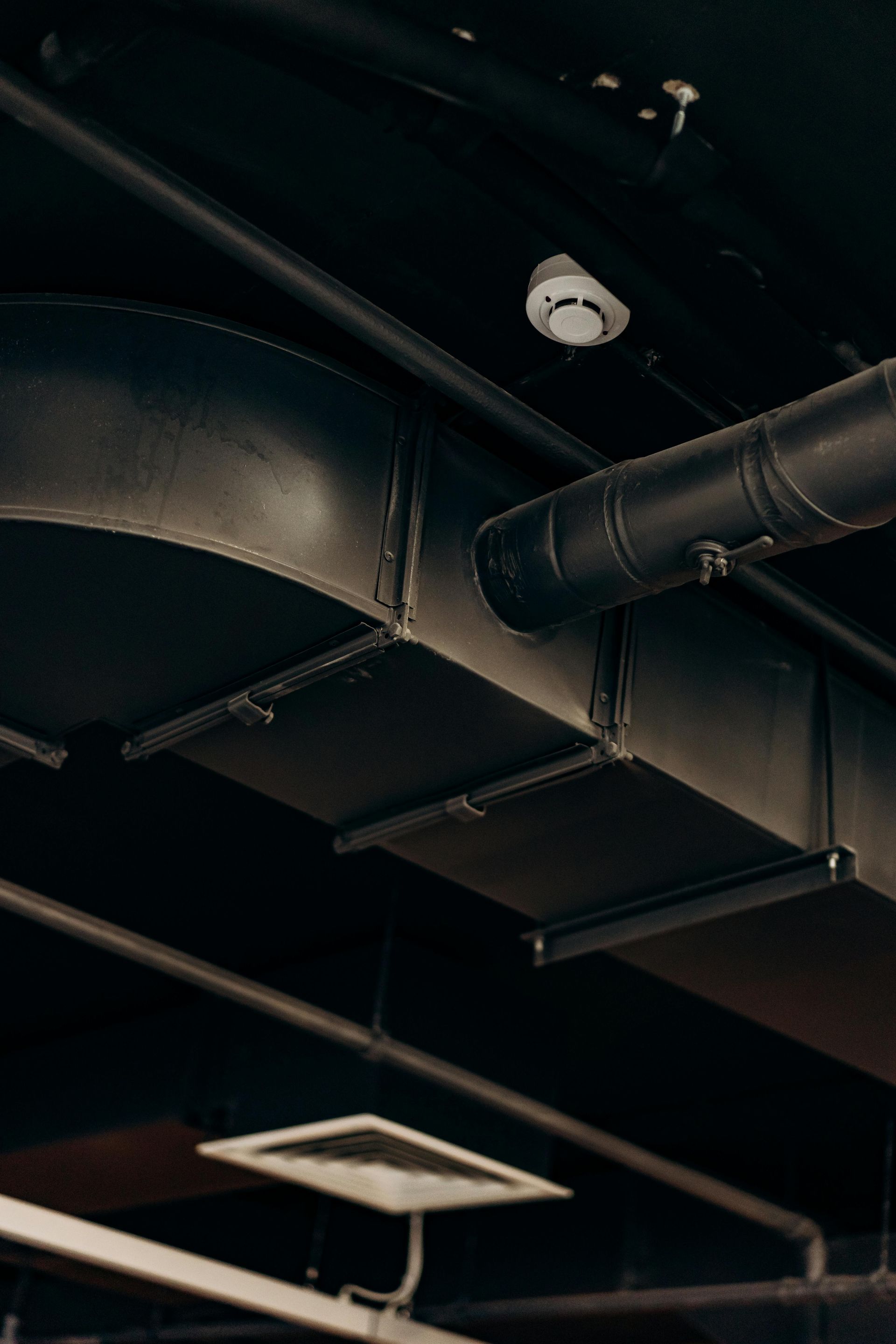 A black pipe is hanging from the ceiling of a building.