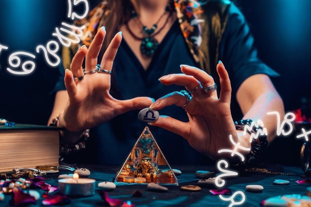 Fortune teller holds a stone with a Libra symbol, surrounded by astrological signs and a crystal pyramid.