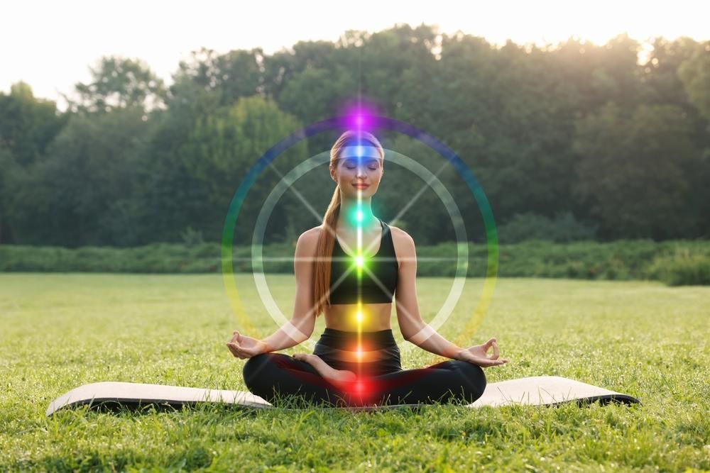 A drawing of a person with chakra colors, surrounded by crystals, candles, and a lantern.