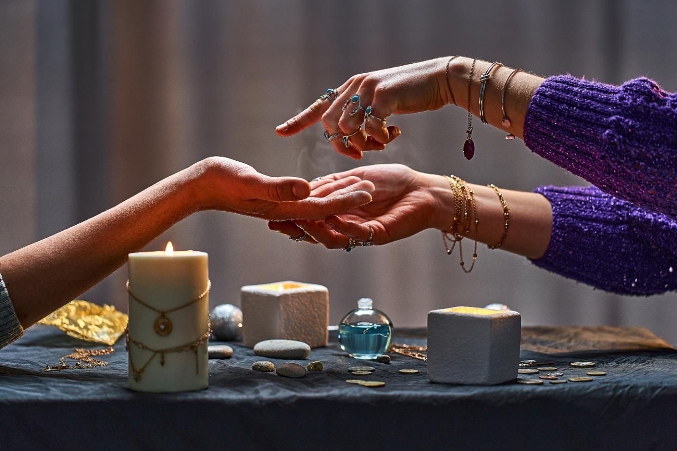 Palm reader examining a client's hand over a table with candles and crystals.