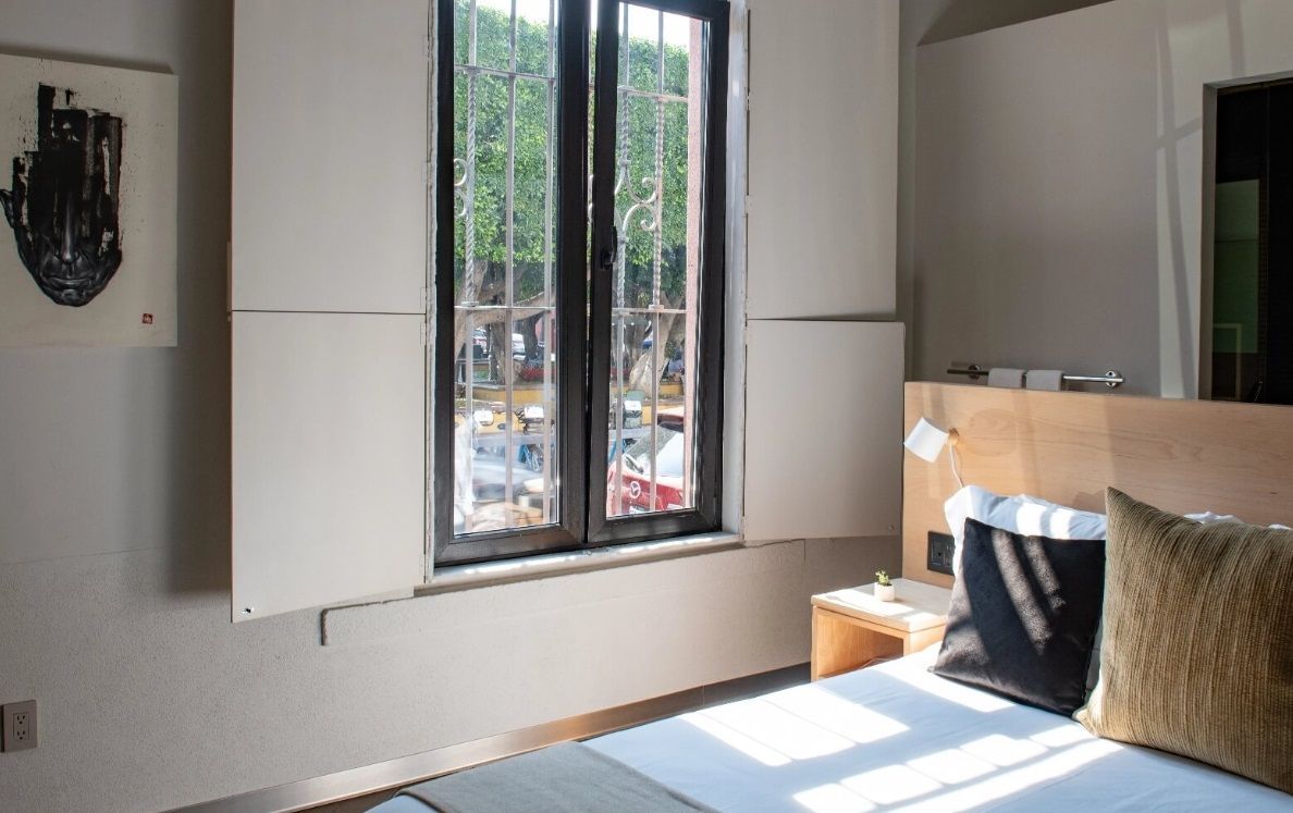 Un dormitorio con una cama y una ventana con persianas abiertas.