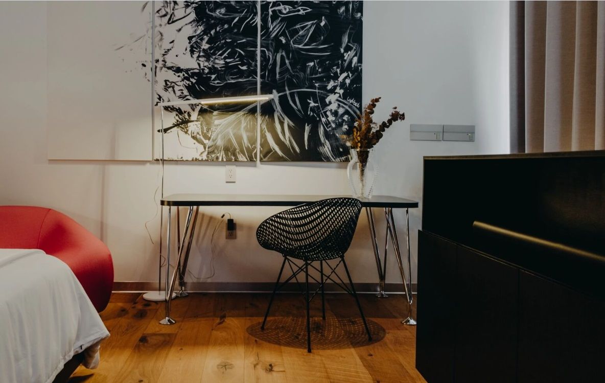 Un dormitorio con un escritorio y una silla y un cuadro en la pared.
