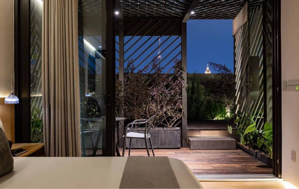 Un dormitorio con una cama grande y una puerta corrediza de vidrio que conduce a un balcón.