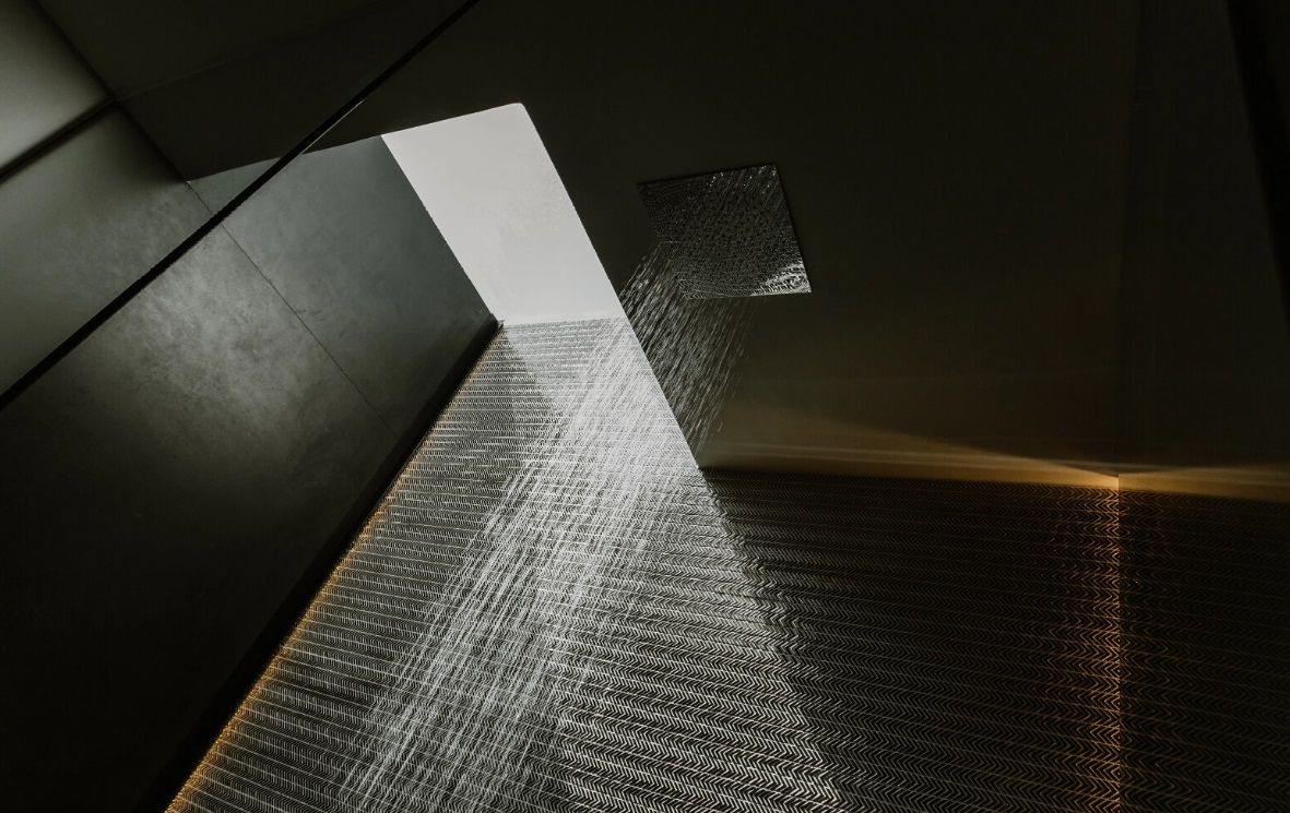 Un cabezal de ducha rocía agua desde el techo en una habitación oscura.