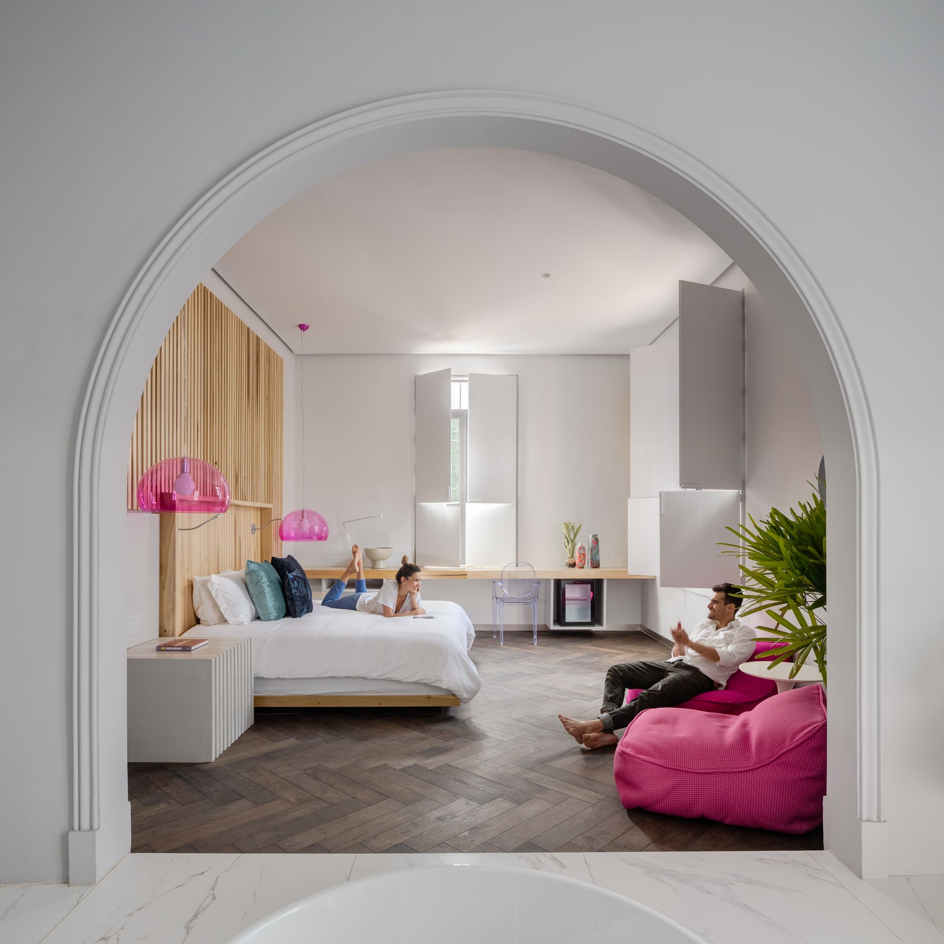 Un dormitorio con una cama grande y un sillón puf rosa.