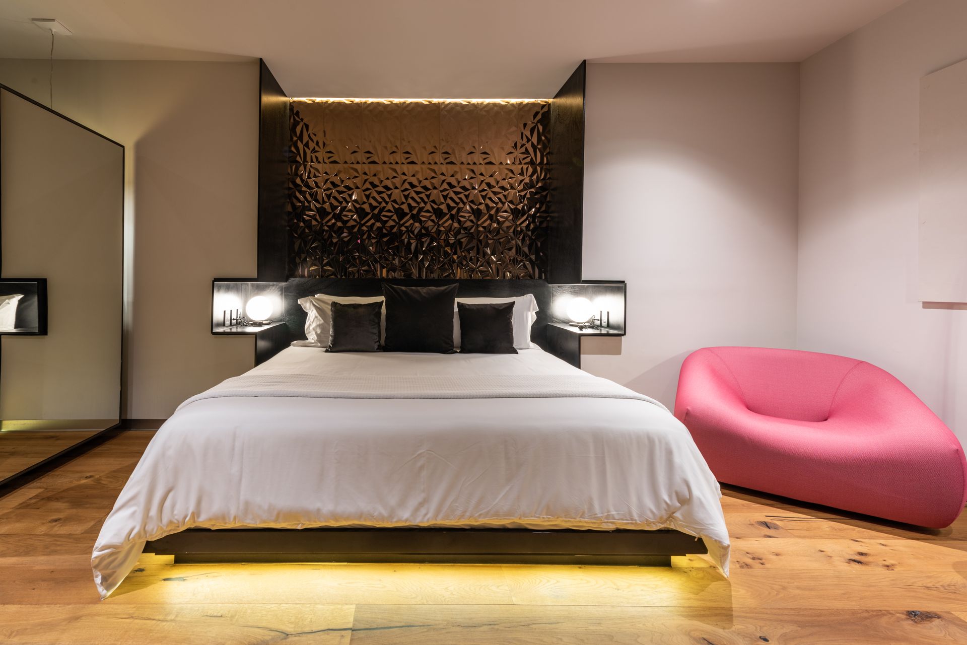 Un dormitorio con una cama grande y una silla rosa.